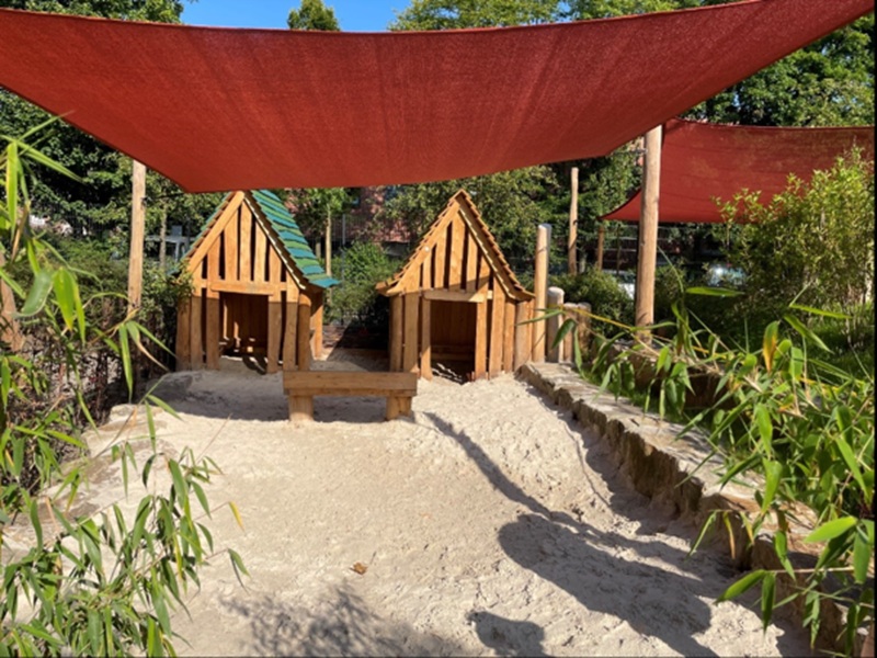 Sandkasten im Garten mit zwei kleinen Spielhäuschen
