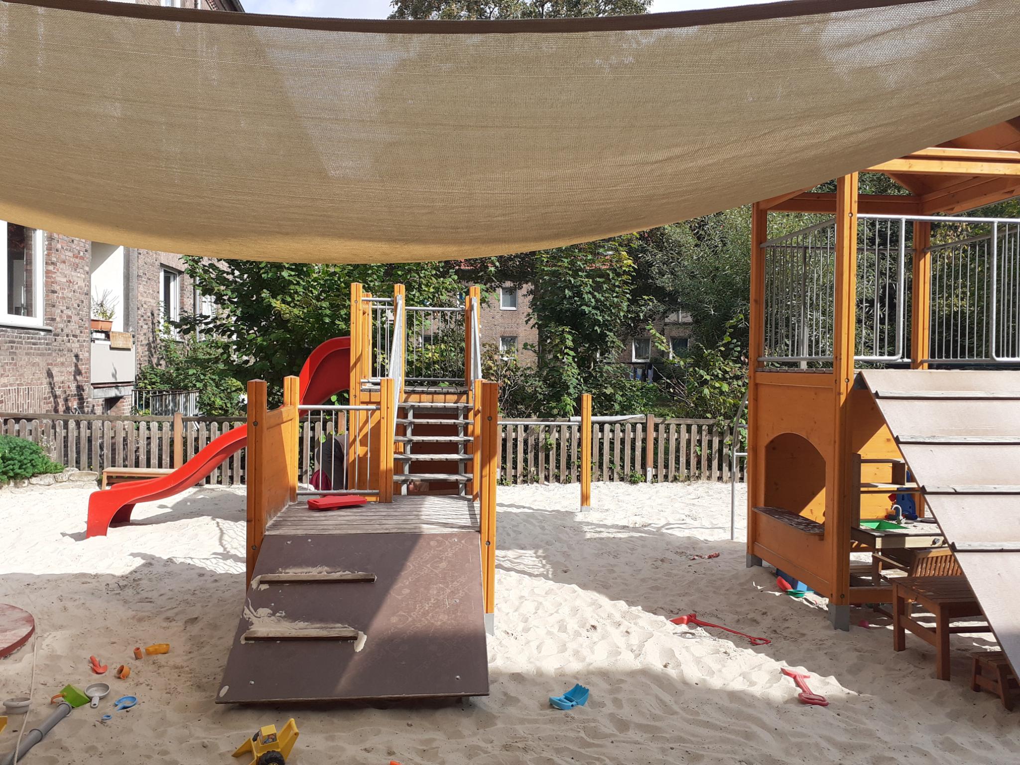Spielbereich mit Sandkasten, zwei Spielgeräten, Schaukel und Trampolin